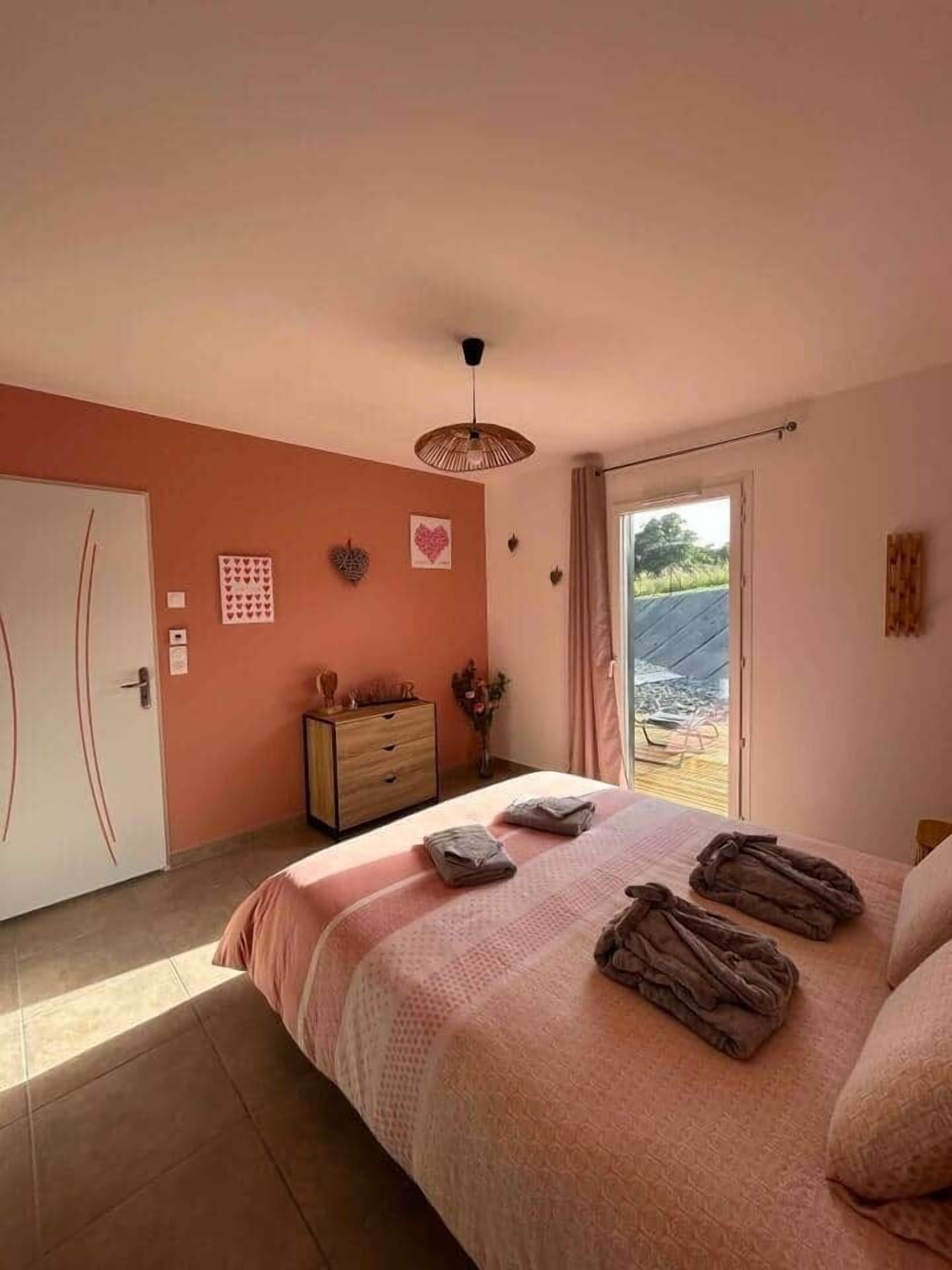 Un dormitori amb llit, un aparador, una porta i vista a l'exterior.