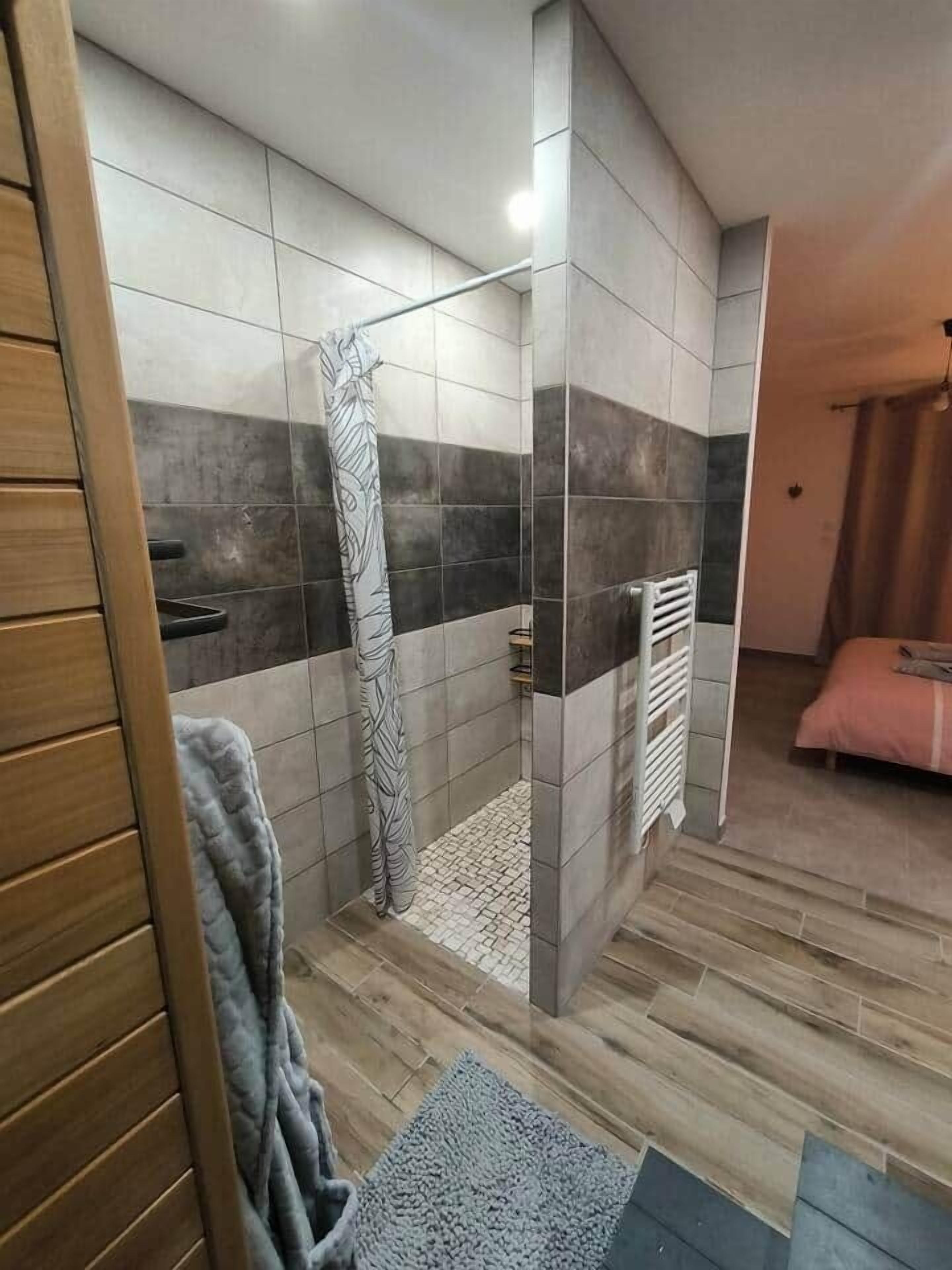 A modern bathroom with a shower, tiled walls, and a wooden floor.