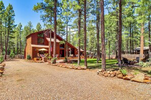 A two-story wooden cabin with a covered porch, surrounded by a forest. - Deck, Fire Pit, Hot Tub! Pinetop Family Cabin (Pinetop)