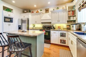 A modern kitchen with white cabinetry, a central island with bar stools, a built-in oven, and a microwave. - Deck, Fire Pit, Hot Tub! Pinetop Family Cabin (Pinetop)