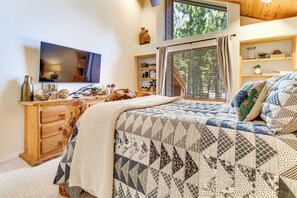 Ein Schlafzimmer mit einem großen Bett, einem Fernseher, Holzmöbeln und einem Fenster mit Jalousien.