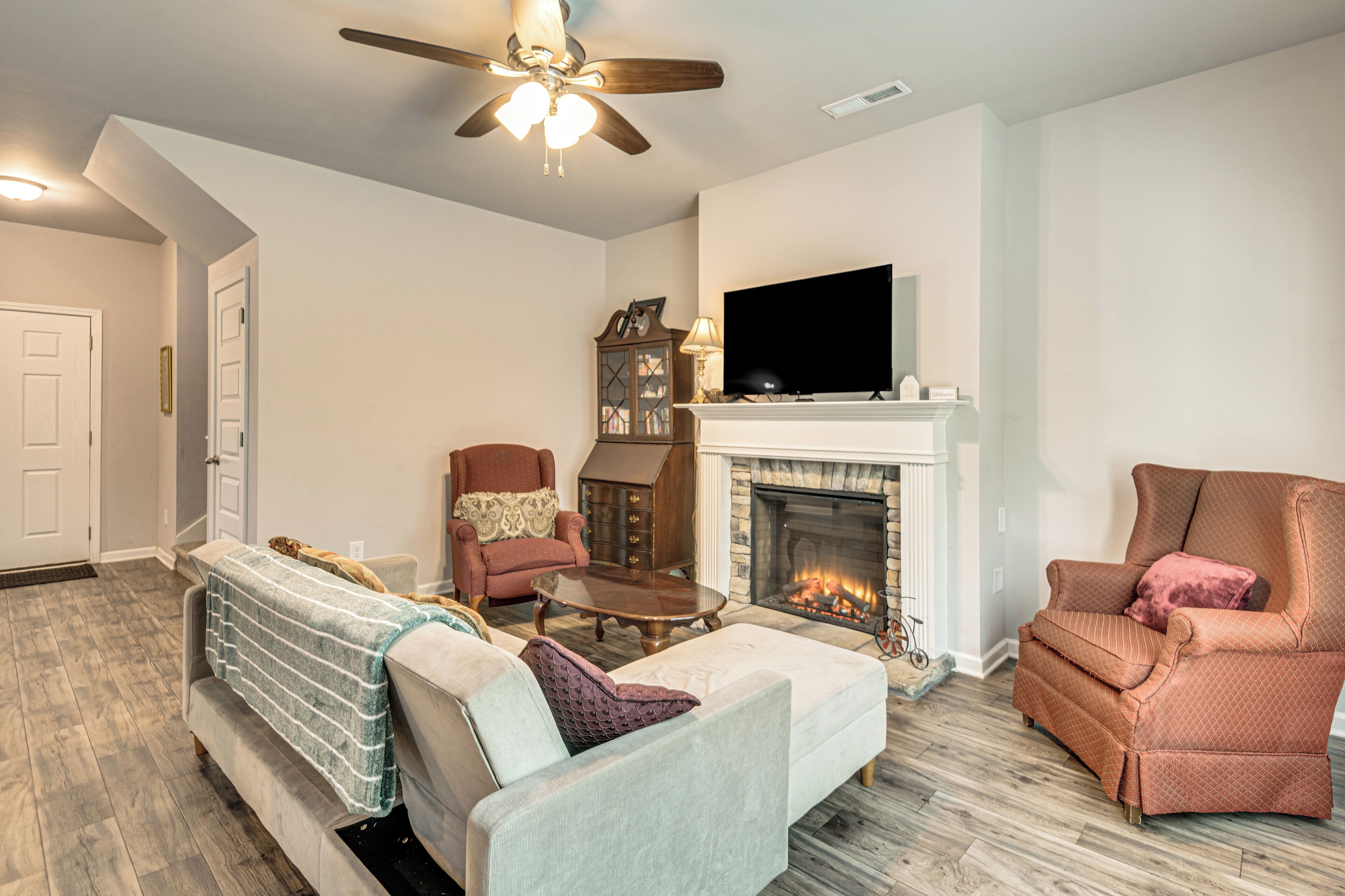 Un salon avec une cheminée, un téléviseur et un ventilateur de plafond.