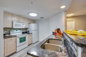 Una cucina moderna con microonde, forno, frigorifero e lavello in acciaio inossidabile.