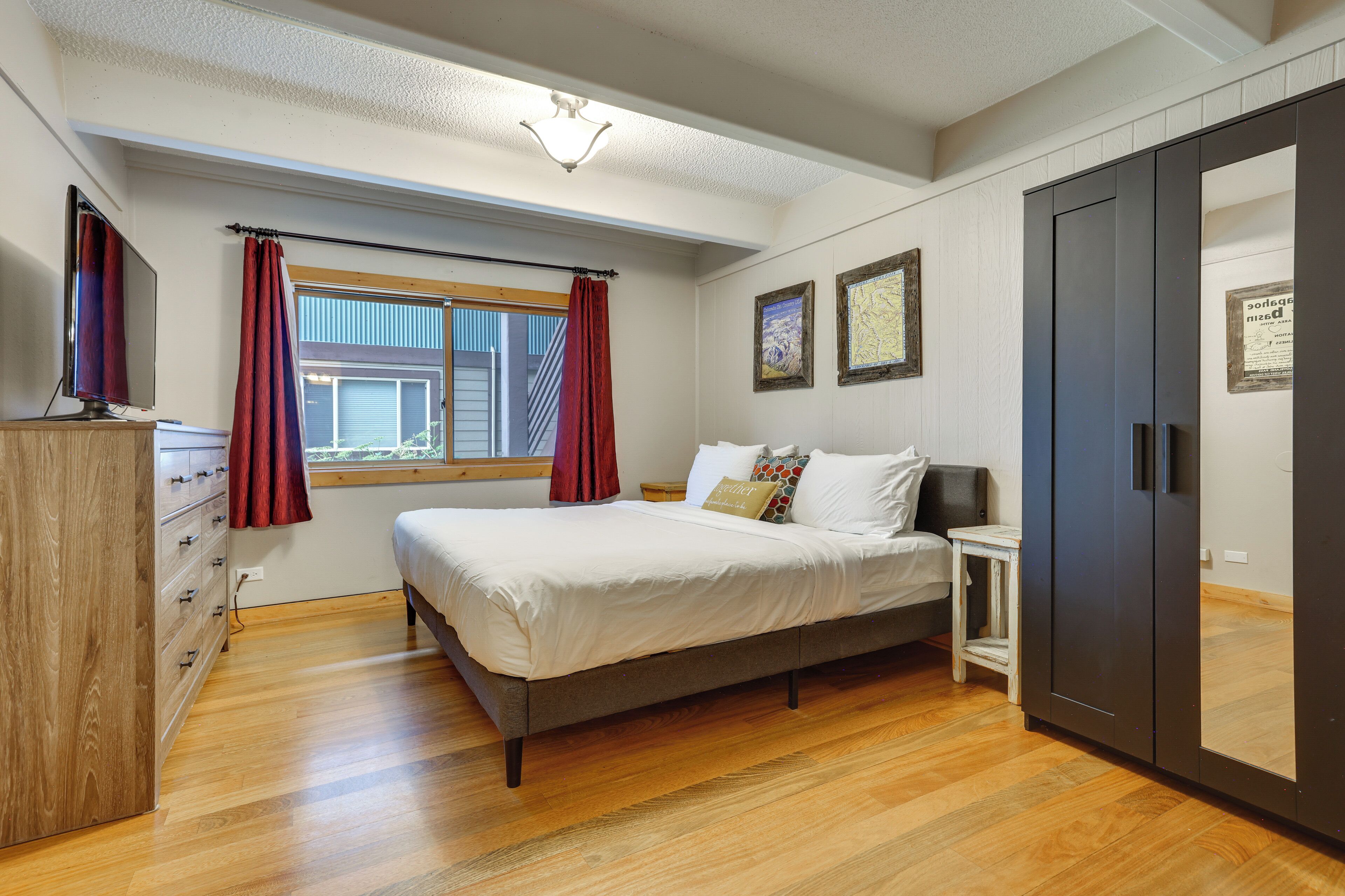A bedroom with a bed, a wardrobe, a desk, and a window with curtains.