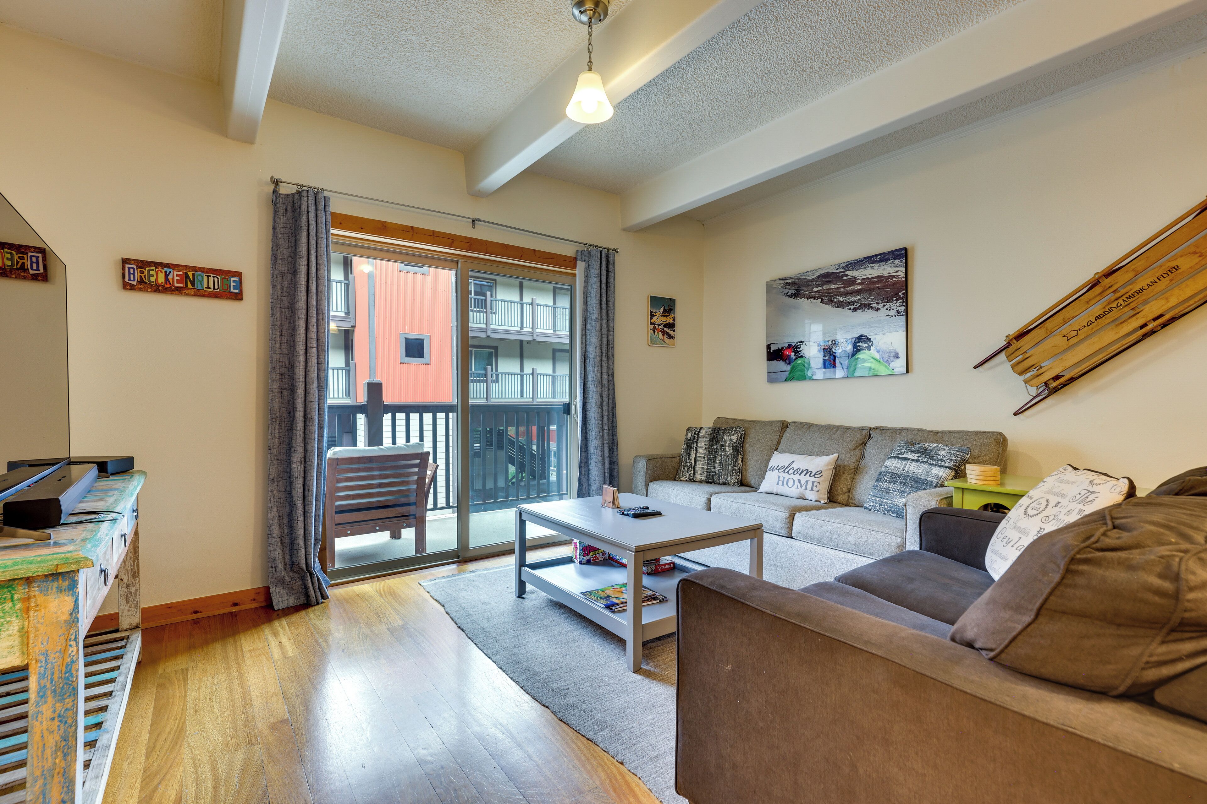 A living room with a sofa, coffee table, and a balcony with a view of a building.