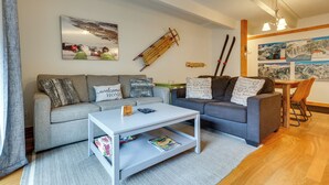 En moderne stue med en grå sofa, et hvidt sofabord og et træspisebord med stole.