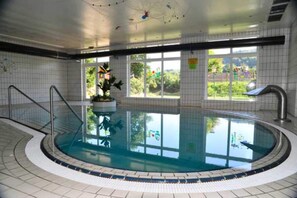 An indoor swimming pool with a tiled floor, a metal ladder, and a window with a view of greenery outside. - Appartement mit All inklusive Angebot und Pool (Runding)