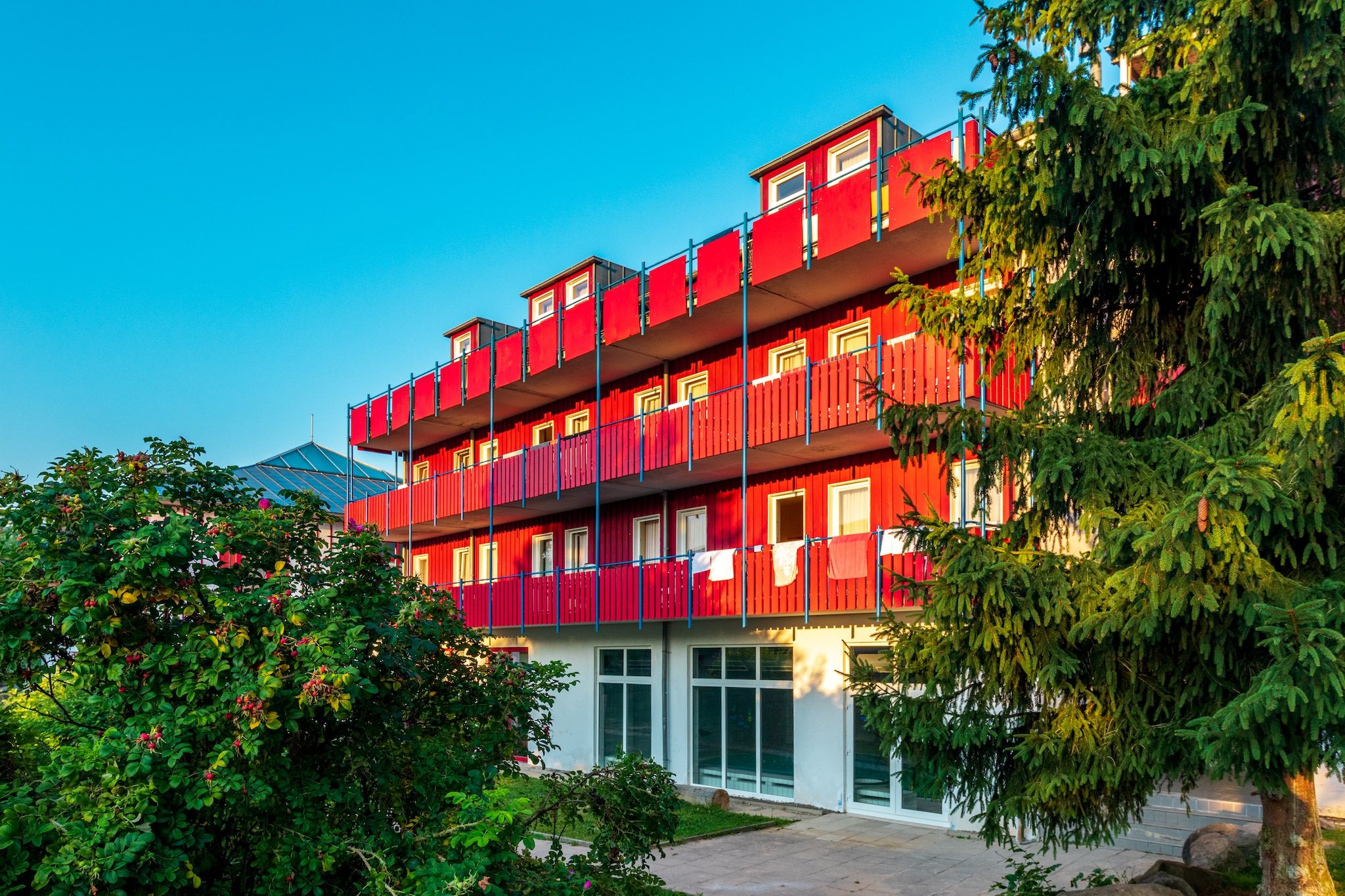 Ein mehrstöckiges Gebäude mit Balkonen, großen Fenstern und blauem Himmel.