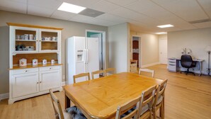 Una cocina amplia con una mesa y sillas de madera, un refrigerador y un armario con utensilios de cocina.