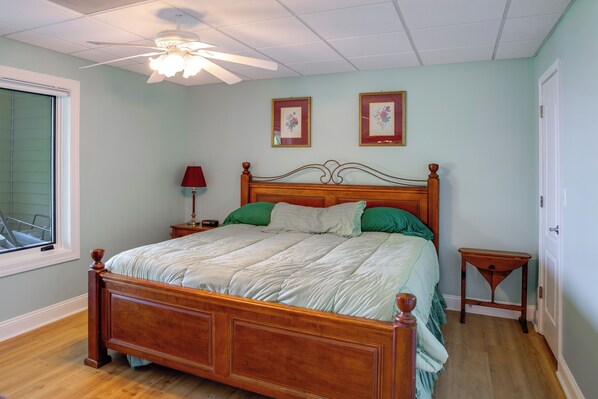 Un dormitorio con una cama de madera, una mesita de noche, una lámpara y dos cuadros en la pared.