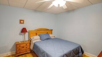 A bedroom with a bed, nightstand, lamp, and a ceiling fan.
