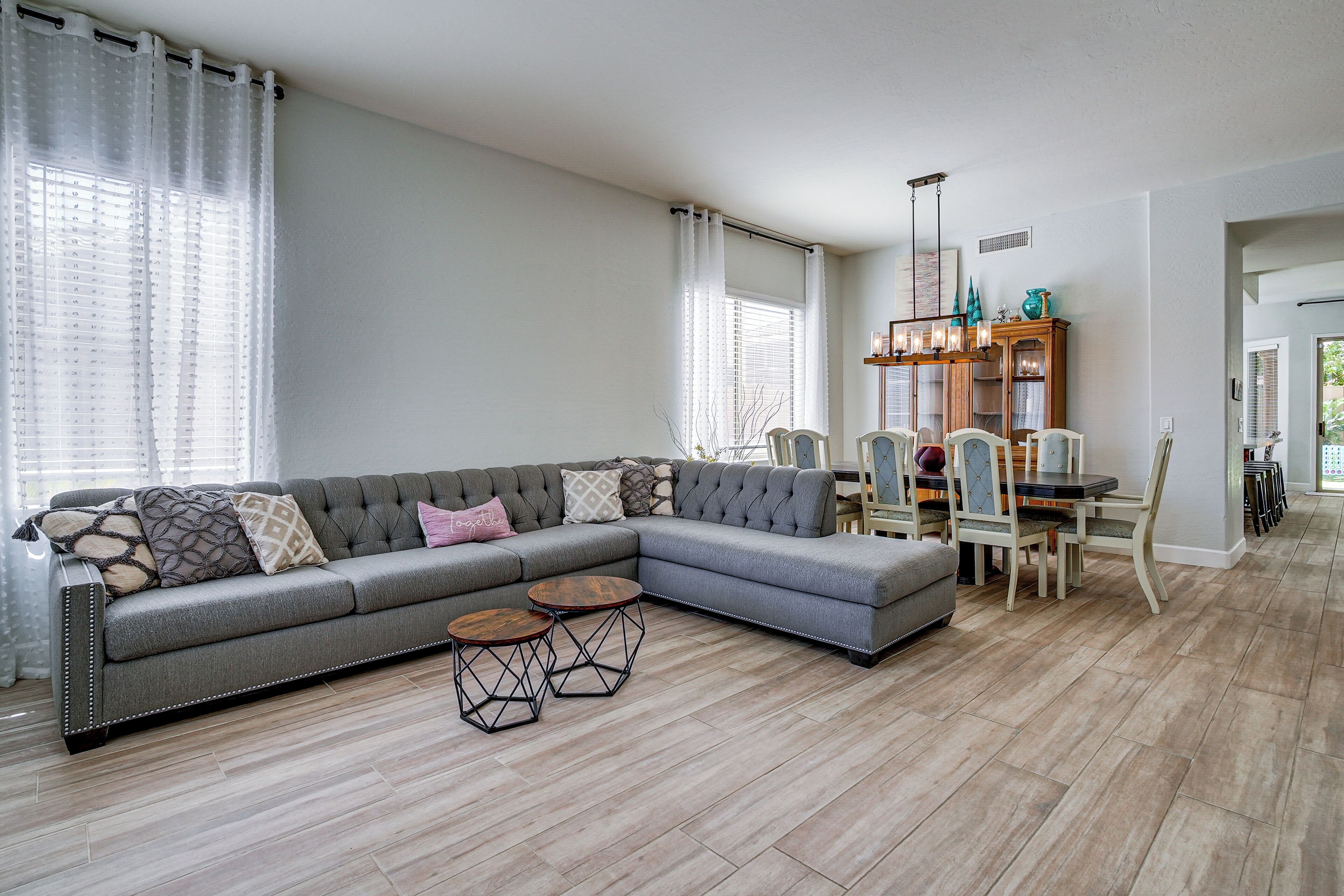 A modern living room with a sectional sofa, a dining table with chairs, and a decorative cabinet.