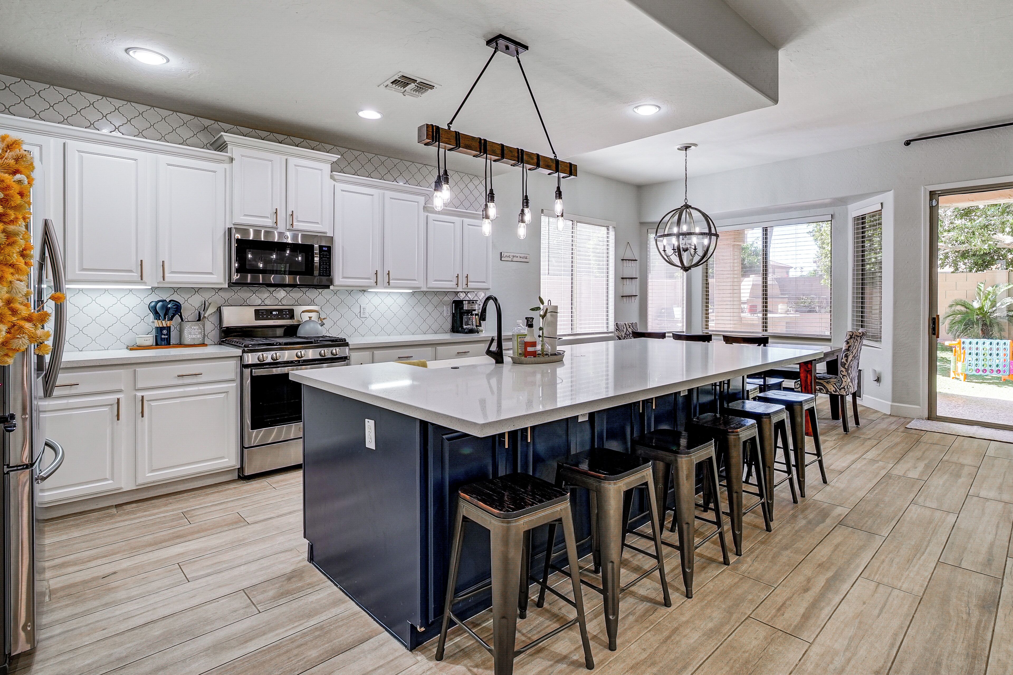 A modern kitchen with white cabinetry, stainless steel appliances, and a central island with bar stools.