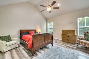 Ein Schlafzimmer mit Bett, Sessel, Kommode und Deckenventilator.