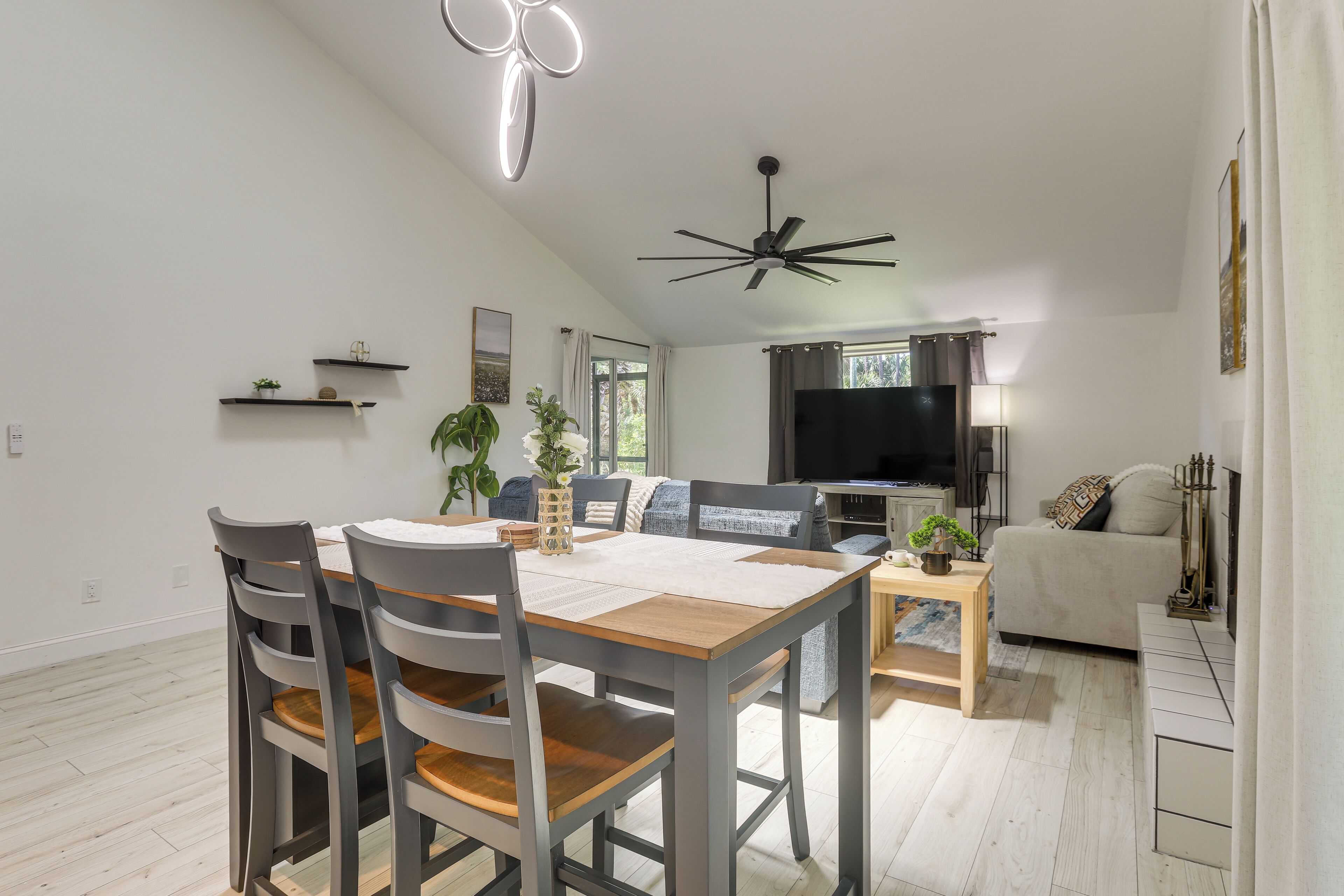 Un salon moderne comprenant un coin repas, un ventilateur de plafond et un téléviseur à écran plat.