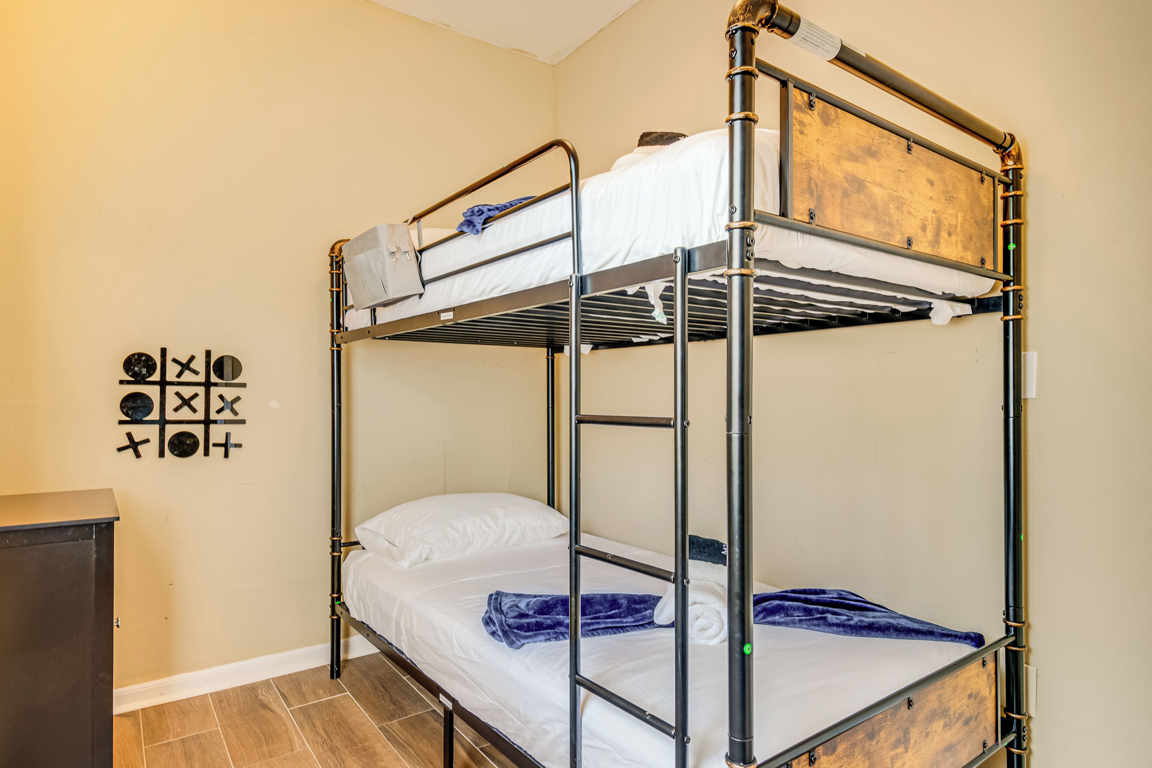 Un lit superposé avec une tête de lit en bois, un petit bureau et un élément décoratif mural.