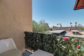 Un balcon donnant sur un immeuble avec un toit rouge et des palmiers.