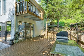 Eine Holzterrasse mit Grill, Glastür und Liegestuhl.