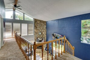 A staircase with wooden balusters leading to a landing with a stone wall and a blue painted wall. - Boat Dock & Slip! Group-Ready Lake Ozark Home (Lake Ozark)