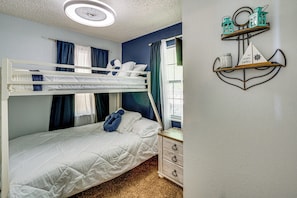 A bunk bed with a white mattress and a single bed with a white mattress. There is a dresser with three drawers and a mirror with a decorative frame. - Boat Dock & Slip! Group-Ready Lake Ozark Home (Lake Ozark)