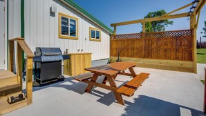 Ein Garten mit Grill, Picknicktisch und Holzzaun.