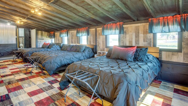 Ein Zimmer mit zwei Betten, einem gemusterten Teppich und einer Decke mit sichtbaren Balken.