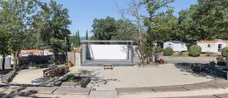 Un amplio espacio al aire libre con un escenario, asientos y cielo despejado.