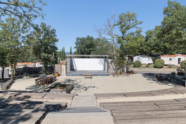 A spacious outdoor area with a stage, seating, and a clear sky.