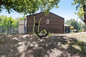 A wooden building with a metal fence and a sculpture in front.