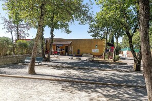 A building with a tiled roof, a signboard, and a gravel ground.