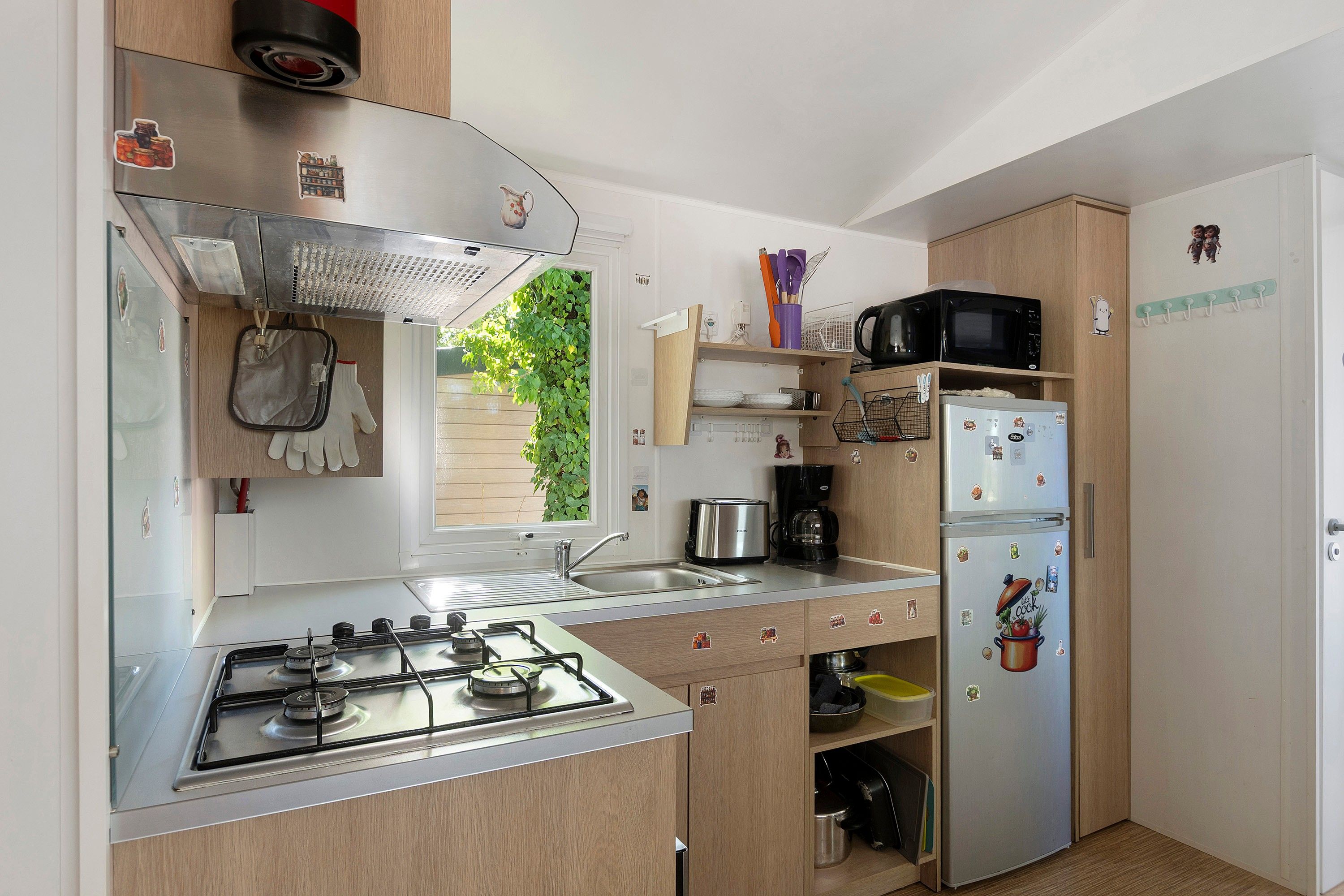 A compact kitchen with a gas stove, a sink, a microwave, and a refrigerator.