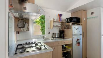 A compact kitchen with a gas stove, a sink, a microwave, and a refrigerator.