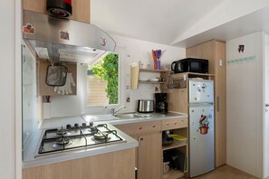 A compact kitchen with a gas stove, a sink, a microwave, and a refrigerator.