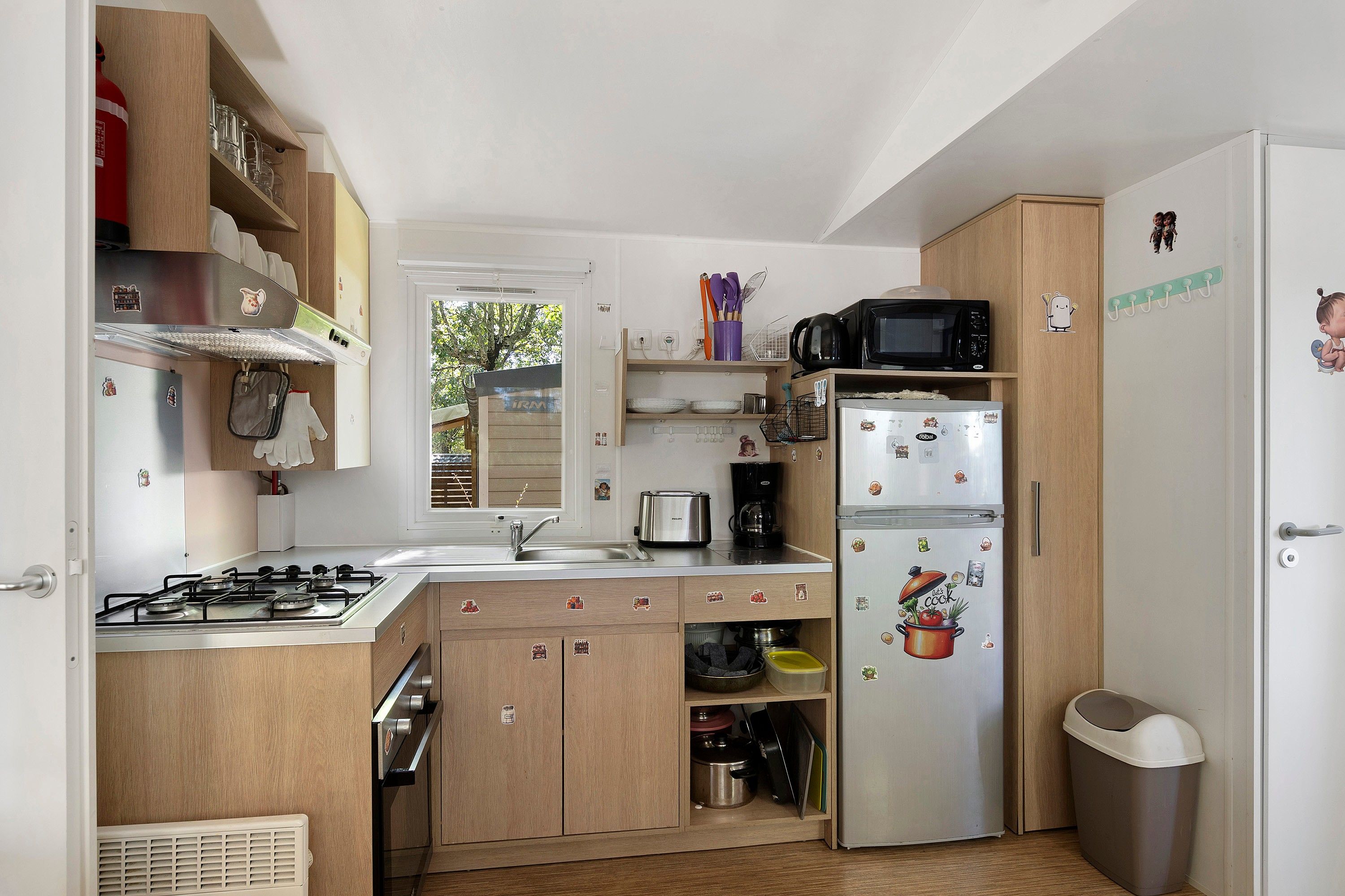 A compact kitchen with a gas stove, a microwave, and a refrigerator.