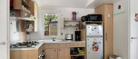 A compact kitchen with a gas stove, a microwave, and a refrigerator.