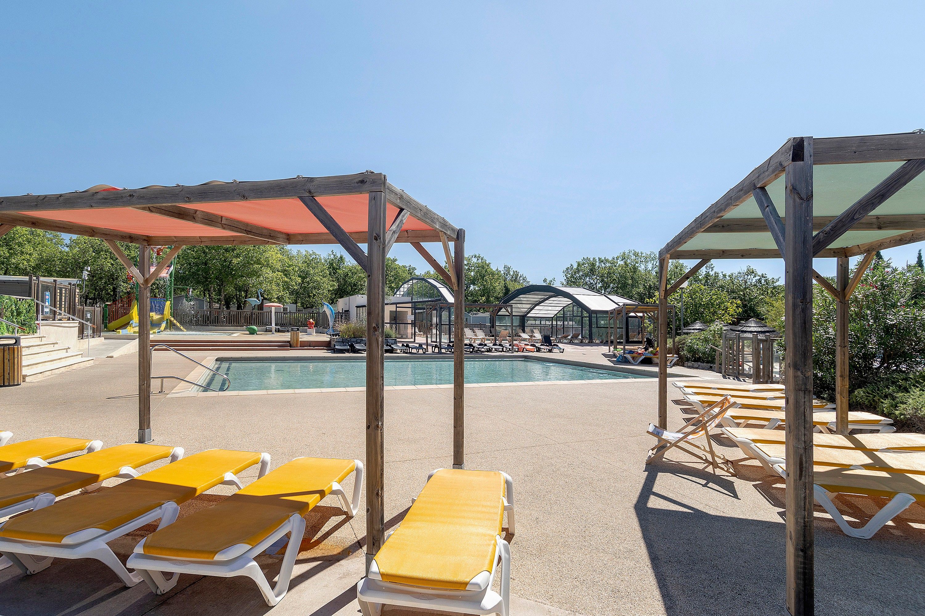 Un espace aménagé au bord de la piscine, avec des chaises longues et un coin salon abrité.