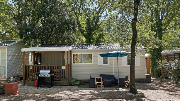 Casa móvil de una habitación con patio, parrilla y mobiliario de exterior.
