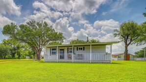 A single-story house with a porch, surrounded by a well-maintained lawn and trees. - Recently Remodeled Route 66 Retreat! Claremore Gem (Claremore)