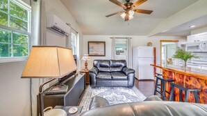 A living room with a leather sofa, a ceiling fan, a TV, and a kitchen area with a refrigerator and microwave. - Recently Remodeled Route 66 Retreat! Claremore Gem (Claremore)