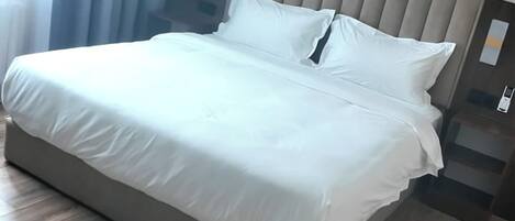 Uma cama com cabeceira, mesa de cabeceira e telefone fixado na parede.