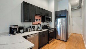 Une cuisine moderne avec des meubles de couleur sombre, des appareils électroménagers en acier inoxydable et un plan de travail en marbre.