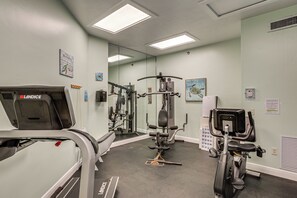 Ein Fitnessstudio mit verschiedenen Trainingsgeräten, darunter Laufband, Kraftgeräte und ein Ergometer.