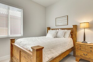 Ein Schlafzimmer mit einem Holzbett, weißer Bettwäsche, einer Nachttischlampe, einem Nachttisch und einem an der Wand befestigten Schild.