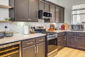 A modern kitchen with dark wood cabinets, stainless steel appliances, and a marble countertop. - Indian Palms Retreat Across From Empire Polo Club (Indio)