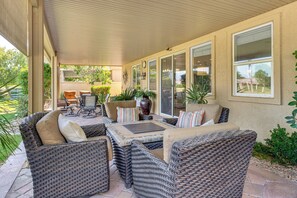Ein überdachter Patio-Bereich mit Korbmöbeln, einem Tisch und einem Stuhl.