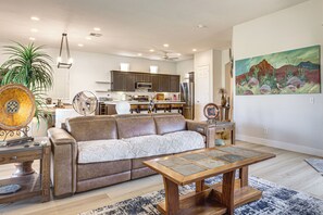 A modern living room with a leather sofa, a wooden coffee table, and a kitchen in the background. - Indian Palms Retreat Across From Empire Polo Club (Indio)