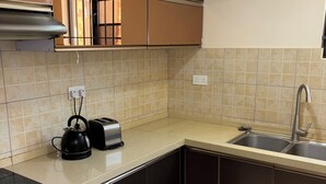 A kitchen with a built-in oven, a kettle, a toaster, and a sink. - Flat near American international school (Lusaka)
