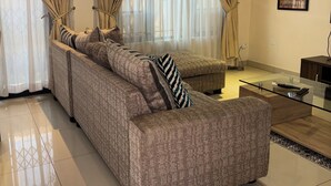 A modern living room with a sofa set, a glass coffee table, and a wall-mounted air conditioner. - Flat near American international school (Lusaka)