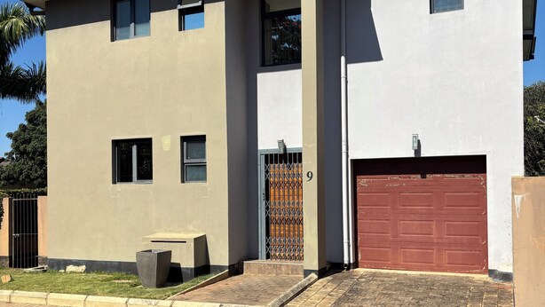 A two-story building with a garage, a gated entrance, and a paved driveway. - Flat near American international school (Lusaka)