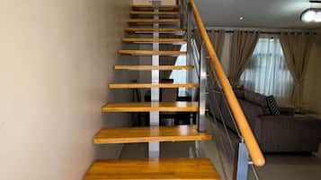 Eine Holztreppe mit Metallgeländern führt zu einem Wohnbereich mit einer Couch.